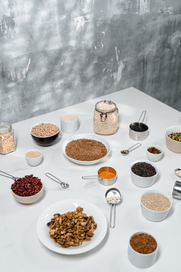 Top view of various organic ingredients including nuts, seeds, and beans arranged on a white table.