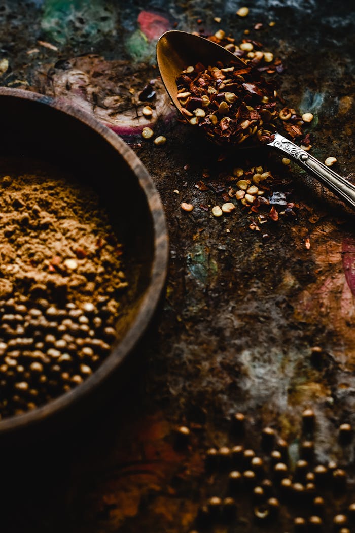 A close-up of chili flakes and ground spices in a rustic setting with a spoon.